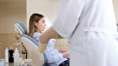 Diş hekimi hastayla çalışmaya hazır eldiven giyer