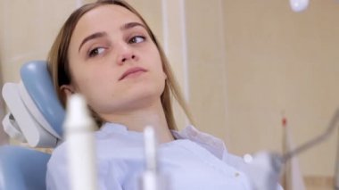 Bir kız bir diş hekimleri sandalyede gülümsüyor ve görüşmeler bir doktor ile