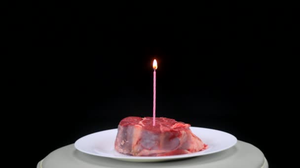 Шматок яловичини з освітленою свічкою в центрі на чорному тлі — стокове відео