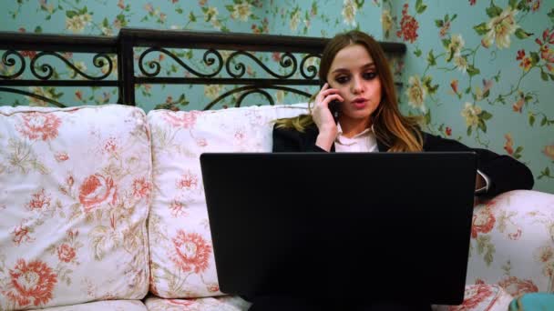 Деловая женщина ссорится по телефону, сидя за ноутбуком — стоковое видео