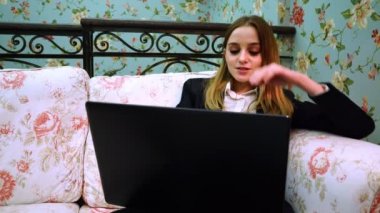 İş kadını olumlu internete rahat bir koltukta oturan bir dizüstü bilgisayar ile iletişim kurar