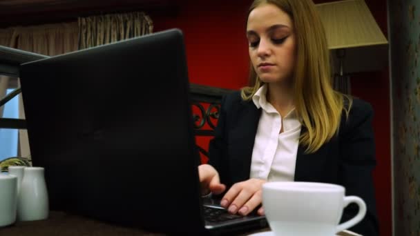 Mujer de negocios escribiendo texto en un portátil sentado en un café sobre una taza de té — Vídeos de Stock