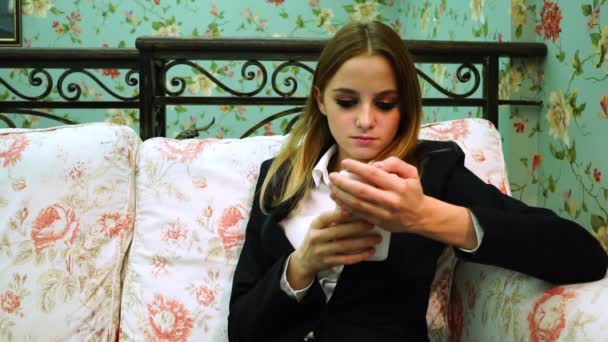 Joven mujer de negocios en traje utiliza teléfono inteligente en el sofá — Vídeos de Stock