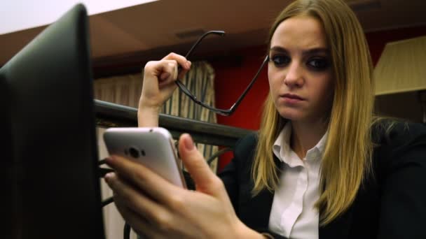 Young business woman looking at the camera holding a smartphone and glasses — Stock Video