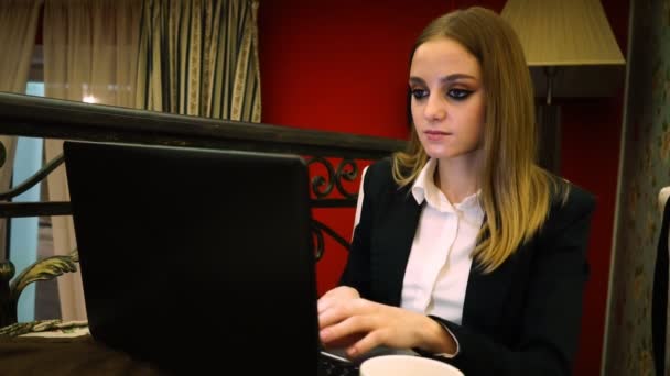 Joven mujer de negocios escribiendo en el texto del ordenador portátil sentado en el restaurante — Vídeos de Stock