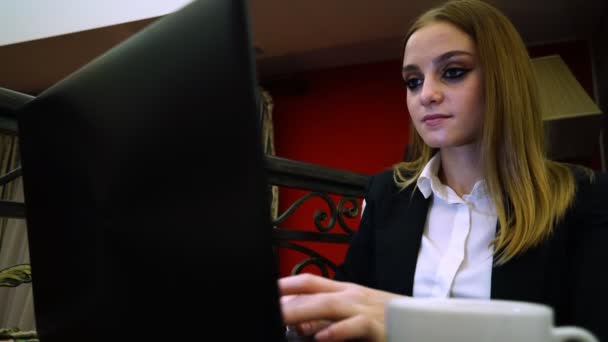 Joven dama de negocios sentado en un ordenador portátil está ganando texto — Vídeo de stock