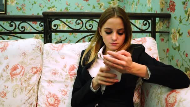 La ragazza in camicia bianca e giacca che tiene il telefono e cerca qualcosa su Internet — Video Stock