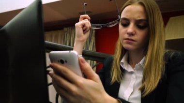 Genç iş kadını düşünceli gözlük tutan smartphone vasıl görünüyor