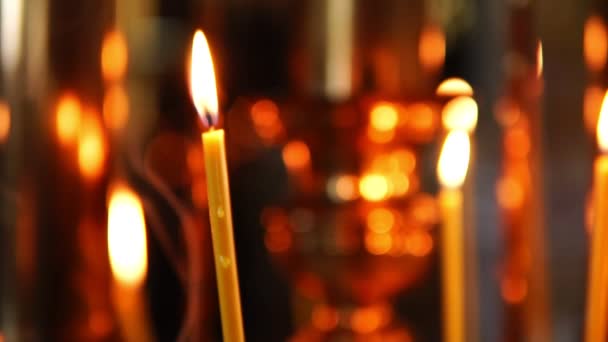 Primer plano de la vela encendida en el fondo de otras velas en la Iglesia Ortodoxa Cristiana — Vídeos de Stock