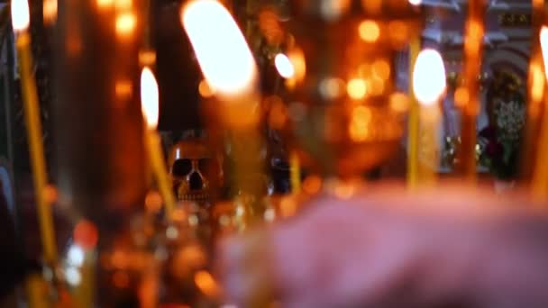 Totenkopf im Fokus, im Vordergrund brennende Kerzen in der christlich-orthodoxen Kirche — Stockvideo