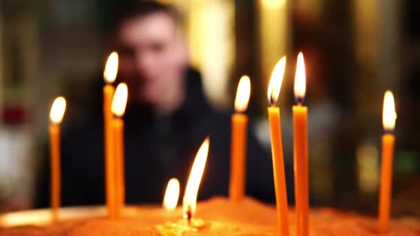 Candele accese in primo piano, l'uomo in secondo piano sfocato — Video Stock