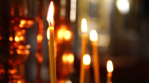 Eine brennende Kerze im Brennpunkt, die orthodoxe Kirche — Stockvideo