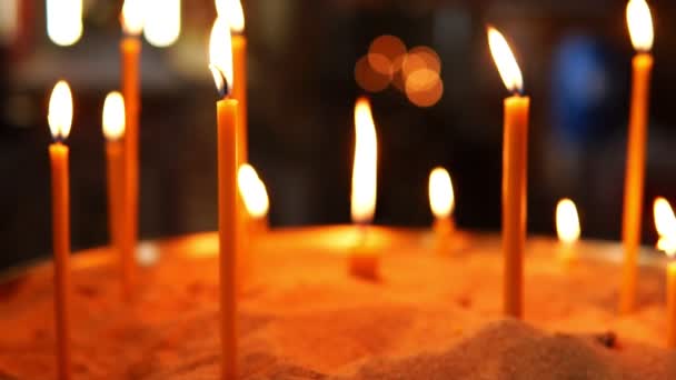 Brandende kaarsen in het zand in de christelijk-orthodoxe kerk — Stockvideo