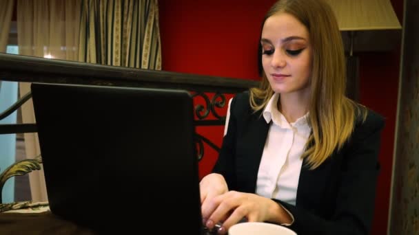 젊은 비즈니스 여자는 레스토랑에 앉아 노트북 텍스트에 입력 텍스트를 말한다 — 비디오