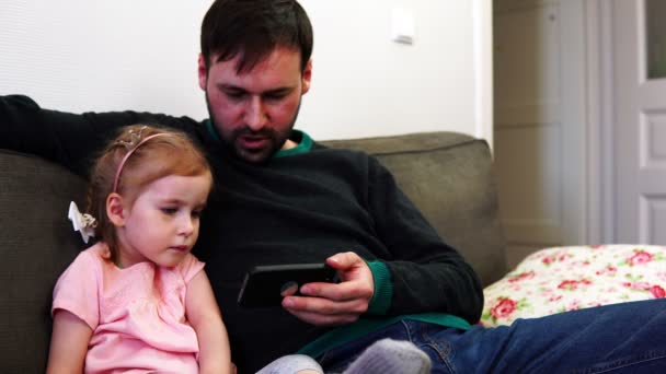 Fiica și tatăl se uită în smartphone și discută despre ceea ce au văzut — Videoclip de stoc