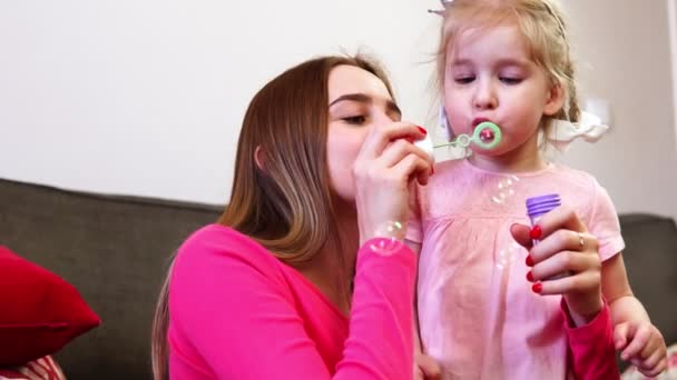 Glückliche Mutter und kleine Prinzessin Tochter blasen Blasen. — Stockvideo