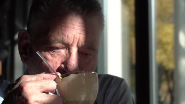 Портрет старшого зморщеного сіроволосатого чоловіка в кафе п'є каву і розмовляє . — стокове відео
