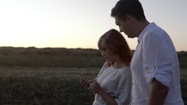 Ζευγάρι ερωτευμένο στέκεται και παρακολουθεί στο smartphone — Αρχείο Βίντεο