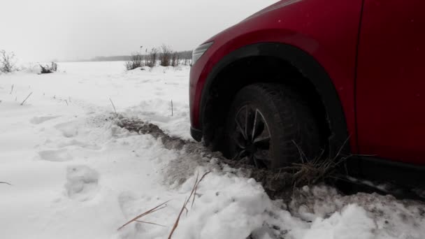 A kocsi beragadt a hóba, és ásott egy lyukat kerékkel, a hóesésben. — Stock videók