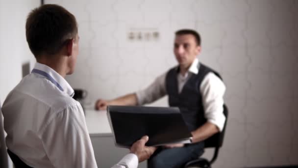 Ein Mann reicht einem anderen Mann im Büro einen Ordner mit Dokumenten — Stockvideo