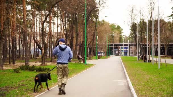 Homme en masque médical marche un grand chien dans la ville déserte — Video