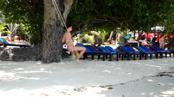 Junge Frau im Bikini schwingt an Holzschaukeln am Strand — Stockvideo