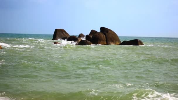 Волна бьет группу камней, стоящих посреди моря — стоковое видео
