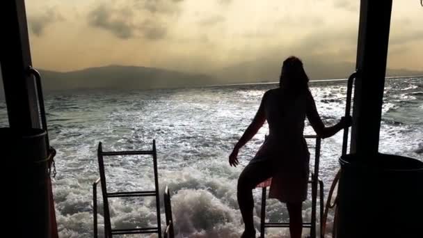 Meisje geniet van de reis aan de achterkant van het schip in de open zee — Stockvideo
