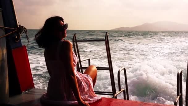 Młoda kobieta w okularach przeciwsłonecznych siedzi i relaksuje się na pokładzie statku — Wideo stockowe