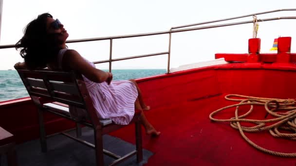 Молодая женщина сидит на скамейке у корма корабля — стоковое видео