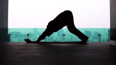 Yogadaki bir adamın silueti metropolün arka planında köpeğe poz veriyor.
