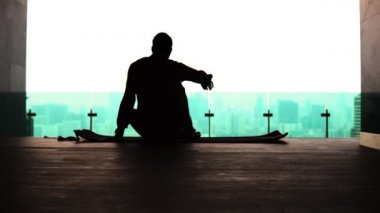 Şehrin arka planında Lotus pozisyonunda oturan bir adamın silueti.