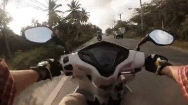 Tayland 'da Samui sokaklarında scooter süren bir adam var.