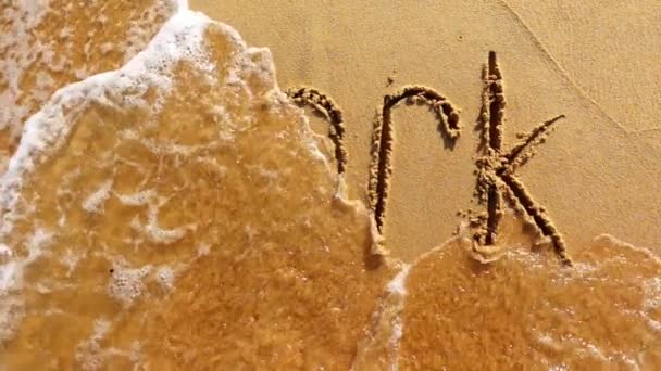 Am Sand gemalte Wortarbeit wird von der Welle abgewaschen — Stockvideo