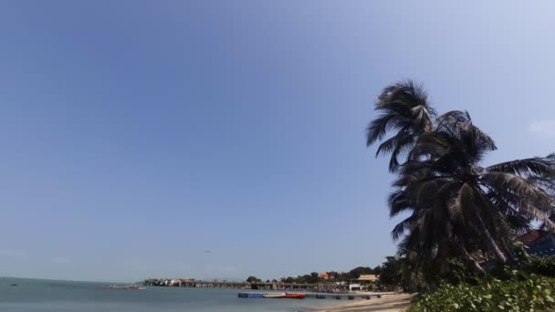 Літак перетинає блакитне небо над водою на тайському пляжі. — стокове відео