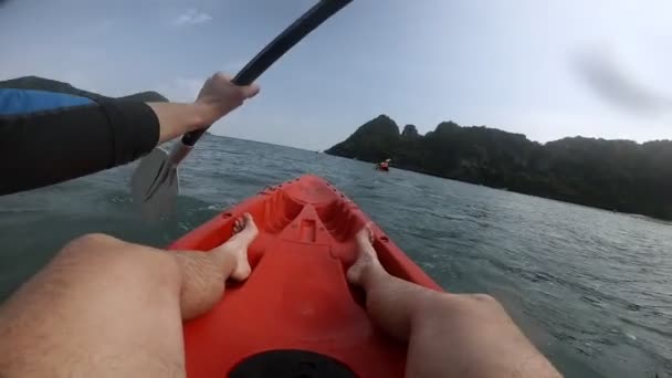 Muž pohybující se černé veslo, aby kajak plavat v blízkosti zelených ostrovů — Stock video