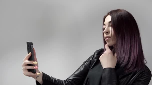 Молодая привлекательная женщина с фиолетовыми волосами делает селфи держа телефон на расстоянии вытянутой руки — стоковое видео