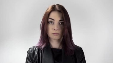 Siyah saçlı genç bir kadının portresi. Üzücü bir şekilde kameraya bakıp duruyor.