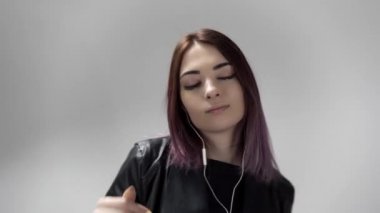 Müzik dinlerken dans eden ve şarkı söyleyen deri ceketli kızın portresi.
