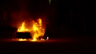 Binanın önünde yanan araba yanıyor.