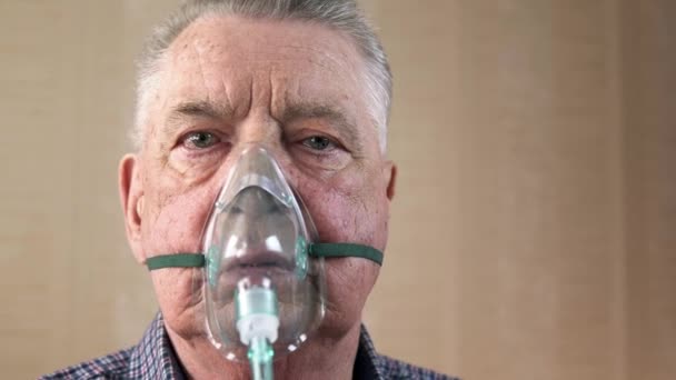 Portret van een oudere man met COPD in een zuurstofmasker ademt diep. — Stockvideo