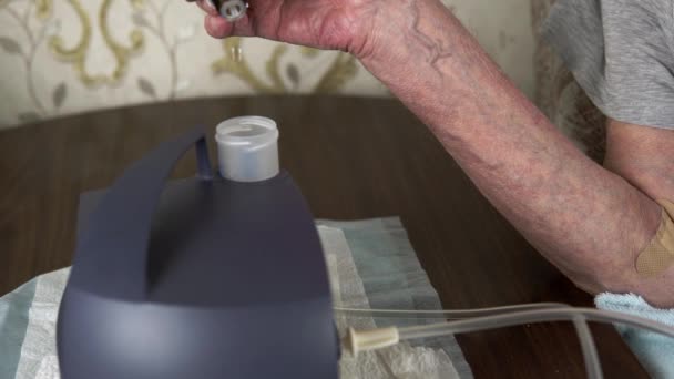 Las manos de los hombres mayores dejan caer la medicina en un inhalador nebulizador. — Vídeos de Stock