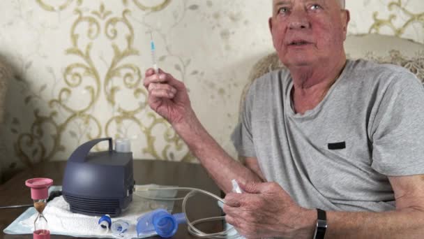 El hombre mayor llena un inhalador nebulizador con medicamentos de una jeringa. — Vídeo de stock