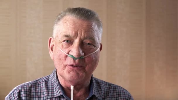 Old man with nasal cannula is watching in the camera and speaking — Stock Video