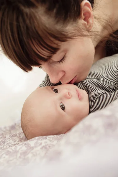 Nuori äiti suutelee vastasyntynyttä vauvaansa . — kuvapankkivalokuva