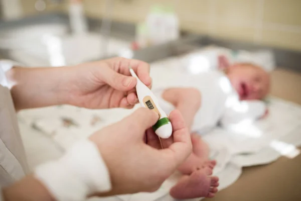 Dettaglio della madre che prende la temperatura del neonato Immagine Stock