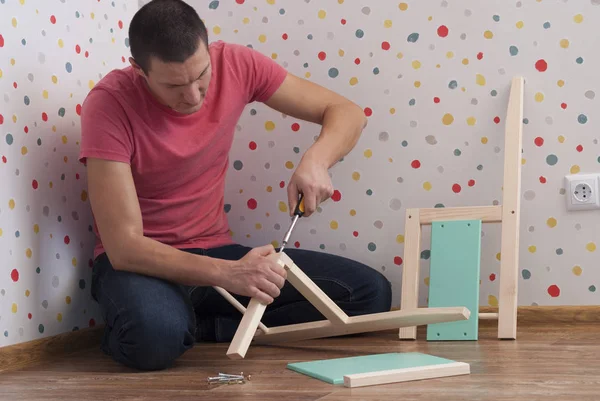 Father assembles a chair for children — Stock Photo, Image