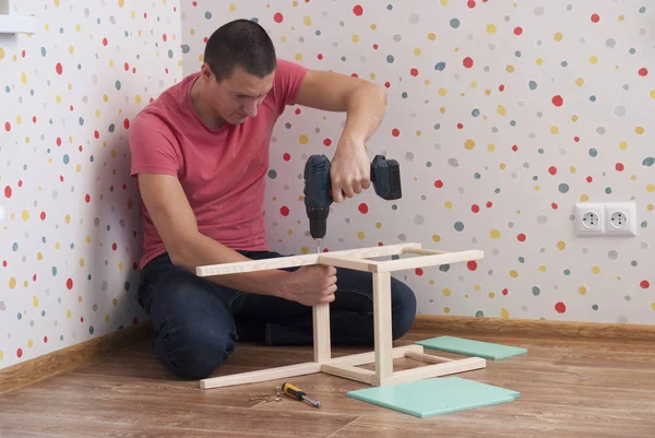 Father assembles a chair for children — Stock Photo, Image