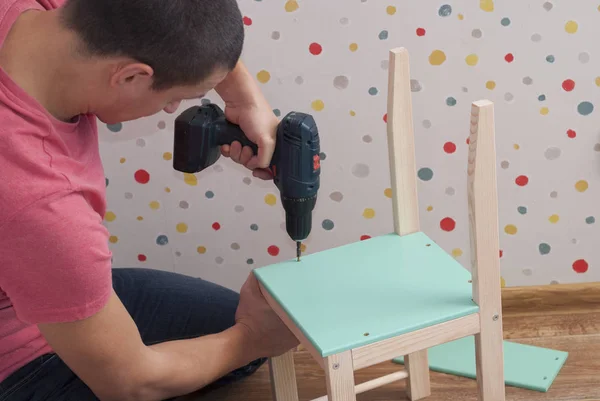 Father assembles a chair for children — Stock Photo, Image