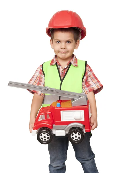 Niño en un casco rojo y con un camión de bomberos en las manos —  Fotos de Stock